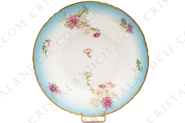 Assiette creuse en porcelaine de Limoges de la maison Sigismond Maas orné de chrysanthèmes rose et blancs sur un fond bleu clair et de liserets or