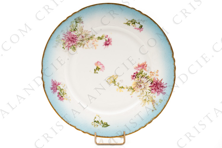 Assiette à dessert en porcelaine de Limoges de la maison Sigismond Maas ornée de chrysanthèmes rose et blancs sur un fond bleu clair et de liserets or