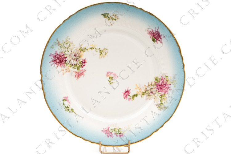 Assiette plate en porcelaine de Limoges de la maison Sigismond Maas ornée de chrysanthèmes rose et blancs sur un fond bleu clair et de liserets or
