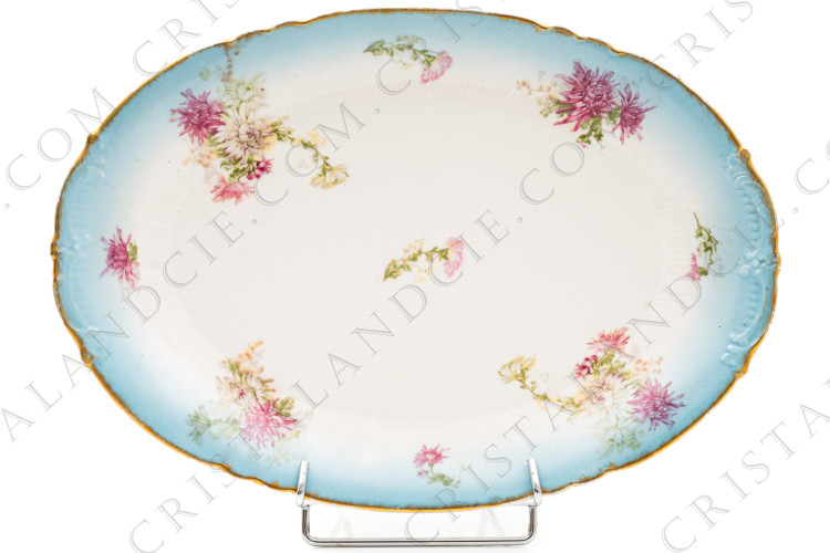 Plat ovale en porcelaine de Limoges de la maison Sigismond Maas orné de chrysanthèmes rose et blancs sur un fond bleu clair et de liserets or